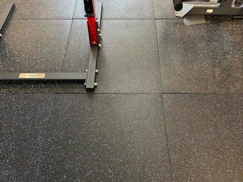 A quality control engineer inspecting a roll of black rubber flooring with measurement tools.